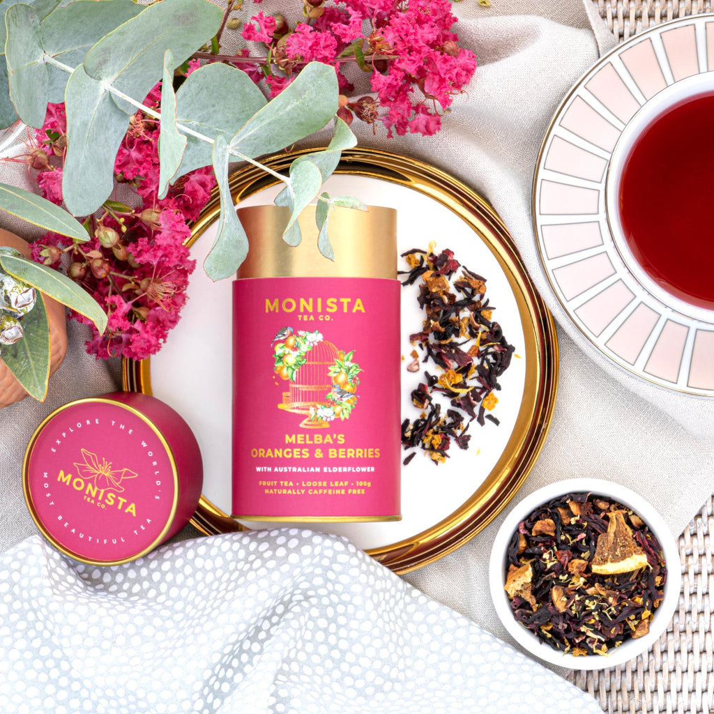 Monista tea packaging with flowers and tea leaves on a white surface