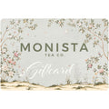 A Monista Tea Co. gift card featuring a soft sage green background decorated with delicate botanical illustrations, pink flowers, small birds, and a sandy landscape at the bottom.