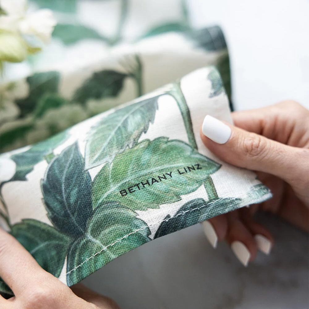 Close-up of folded hydrangea and leaf print linen fabric with a designer's name printed on it