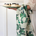 Woman carrying a plate of pavlovas with a hydrangea print tea towel draped over her arm