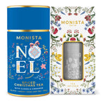 Monista Tea Co. Christmas spiced tea set featuring a blue cylindrical tea tin with gold trim and a matching floral-patterned box containing a silver mesh tea infuser, shown on a white background.