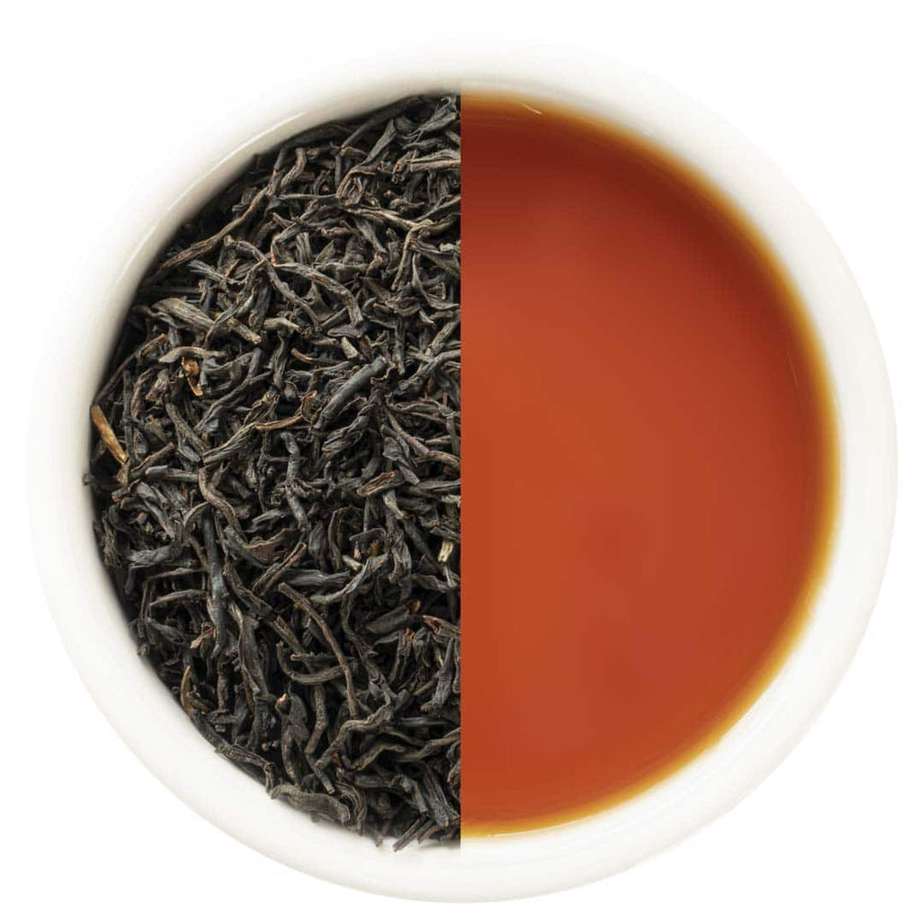 Loose black tea on one side and brewed tea on the other in a white bowl