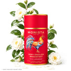 Red tea canister with colorful rooster design and white flowers on a white background