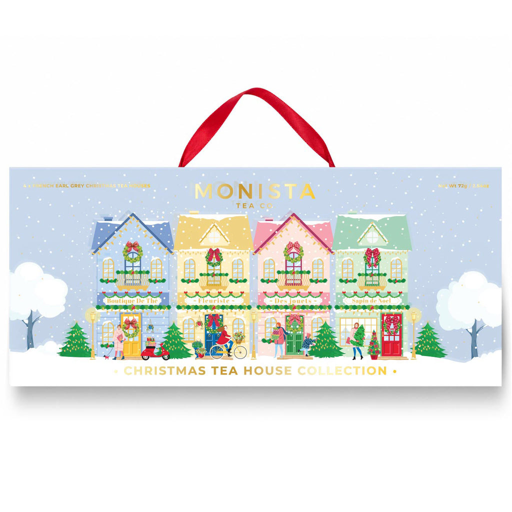 Monista Tea Co Christmas Tea House Collection gift box with a red hanging ribbon, featuring an illustrated winter village scene on a light blue background.