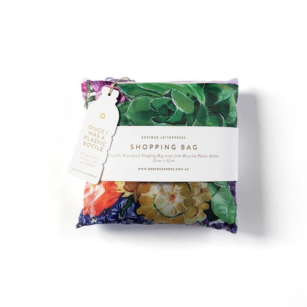 Folded reusable shopping bag with a purple floral print and 'made from recycled plastic bottles' tag
