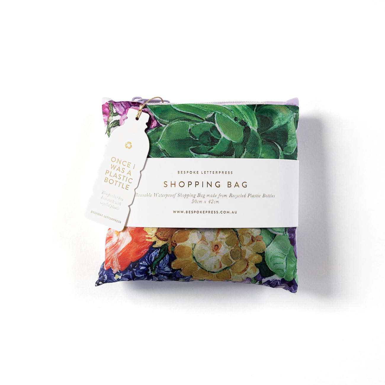 Folded reusable shopping bag with a purple floral print and 'made from recycled plastic bottles' tag