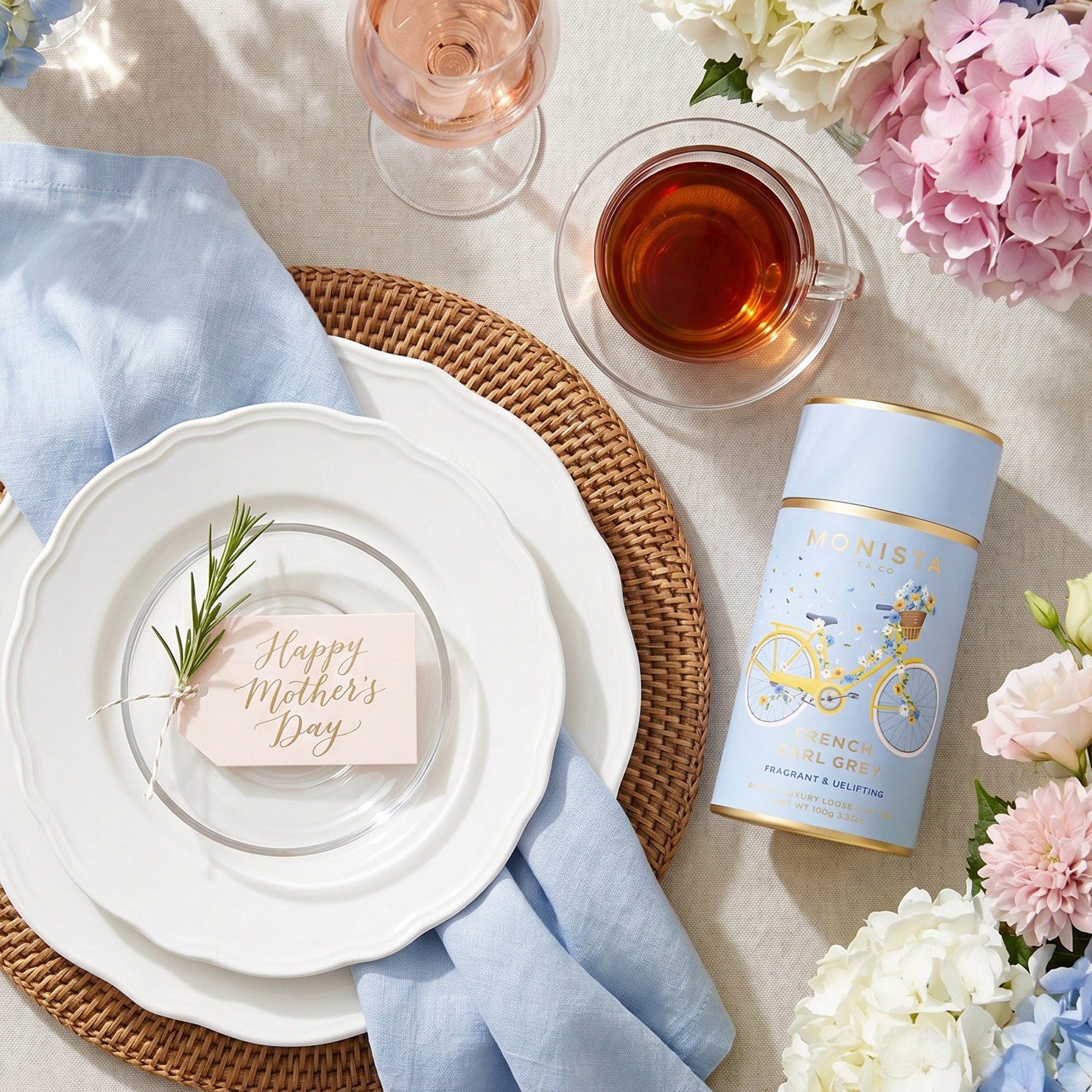 French Earl Grey tea canister on a table setting with a cup of tea, a wine glass, and hydrangeas