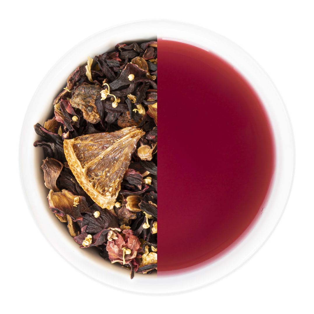 Tea leaves on one side and brewed tea on the other in a white bowl.