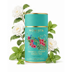 Oriental Garden Green Tea canister surrounded by white camellia flowers and mint leaves on a white background