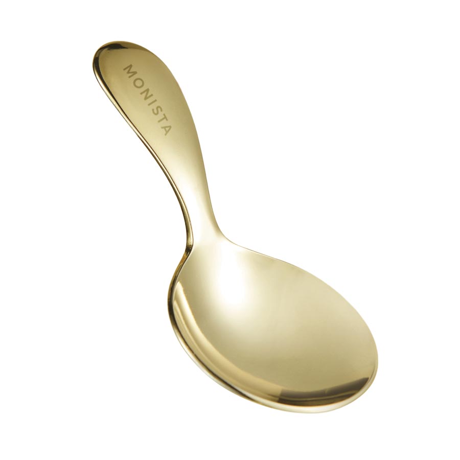 Gold spoon with 'Monista' engraved on the handle on a white background