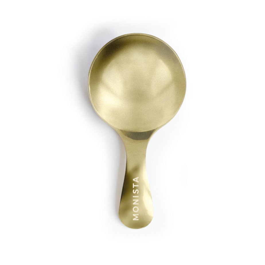 Gold spoon viewed from above with 'Monista' engraved on the handle
