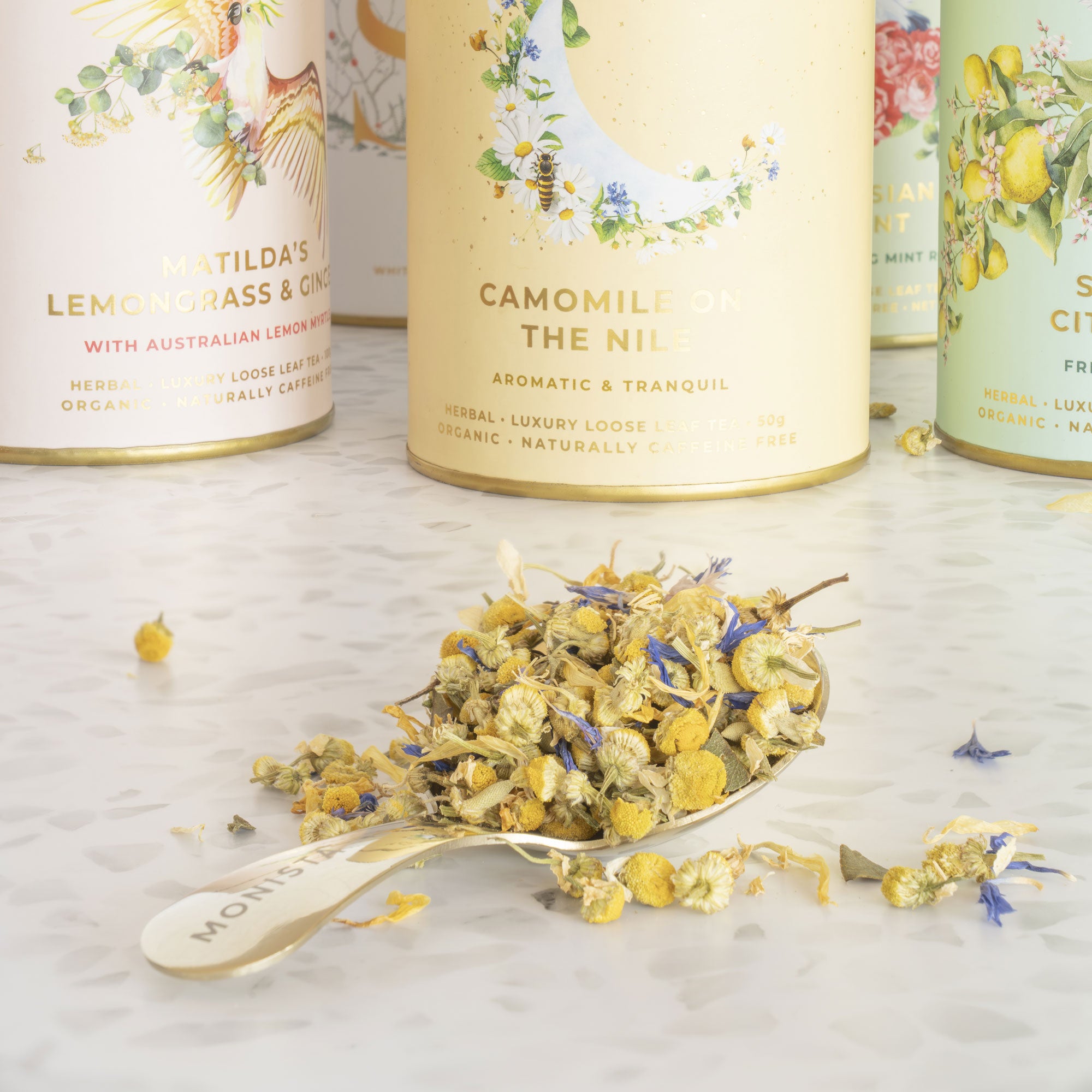 Loose black tea with blue cornflower petals on one side and brewed tea on the other in a white bowl