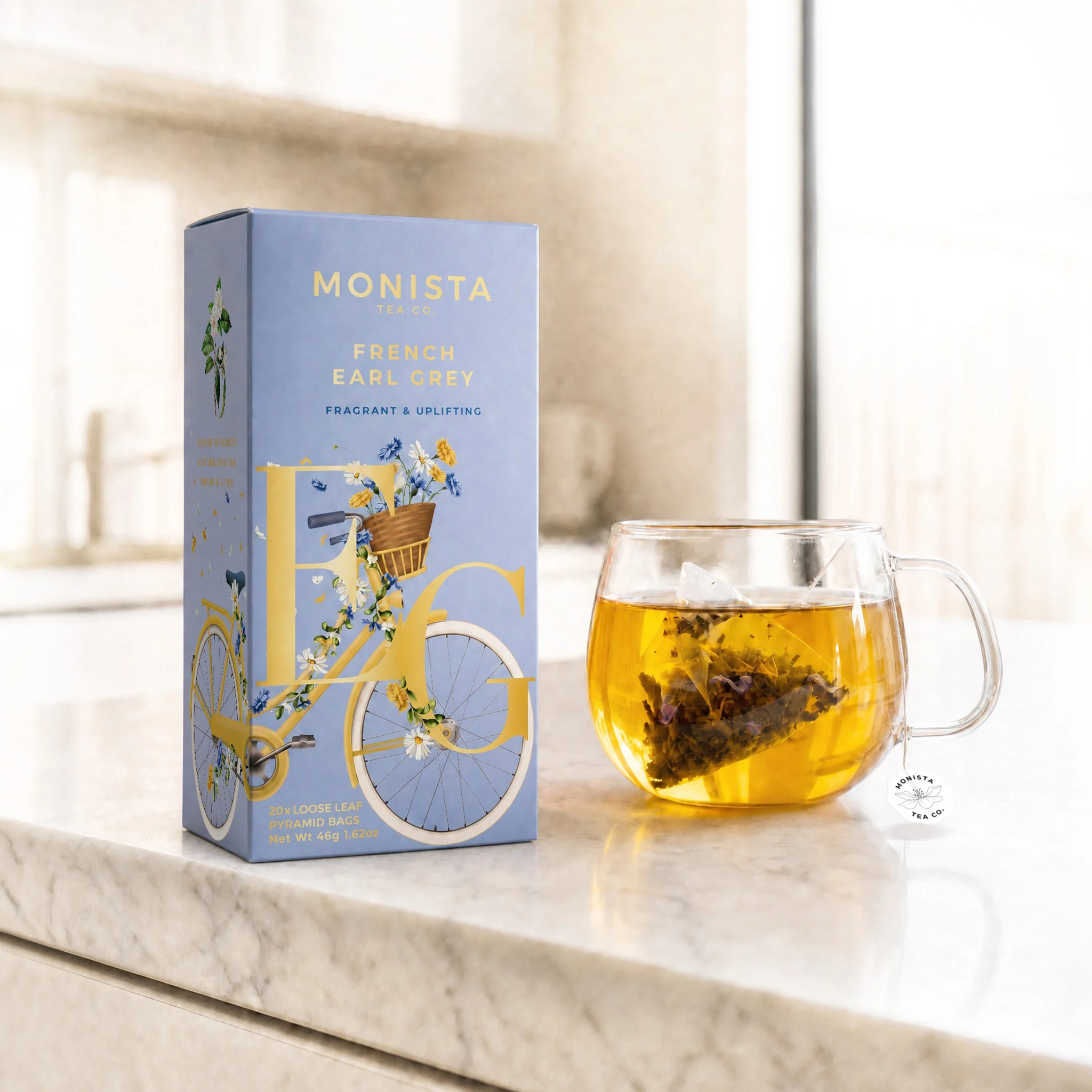 glass tea cup with a tea bag in it with a tea box sitting next to it.