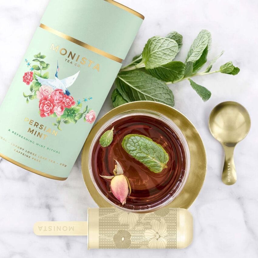 tea canister with mint leaves and gold spoon and infuser
