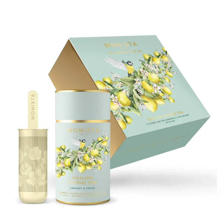 green tea canisters with lemons and a bird on it with gold tea infuser in front of gift box